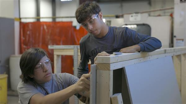 Two students work on a half wall Two students work on a half wall